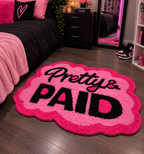 Cloud-shaped hand-tufted rug in hot pink with black "Pretty & Paid" lettering and a scalloped edge.
