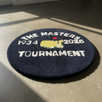 Round hand-tufted navy rug with The Masters Tournament emblem and the years 1934 to 2026 around the border.