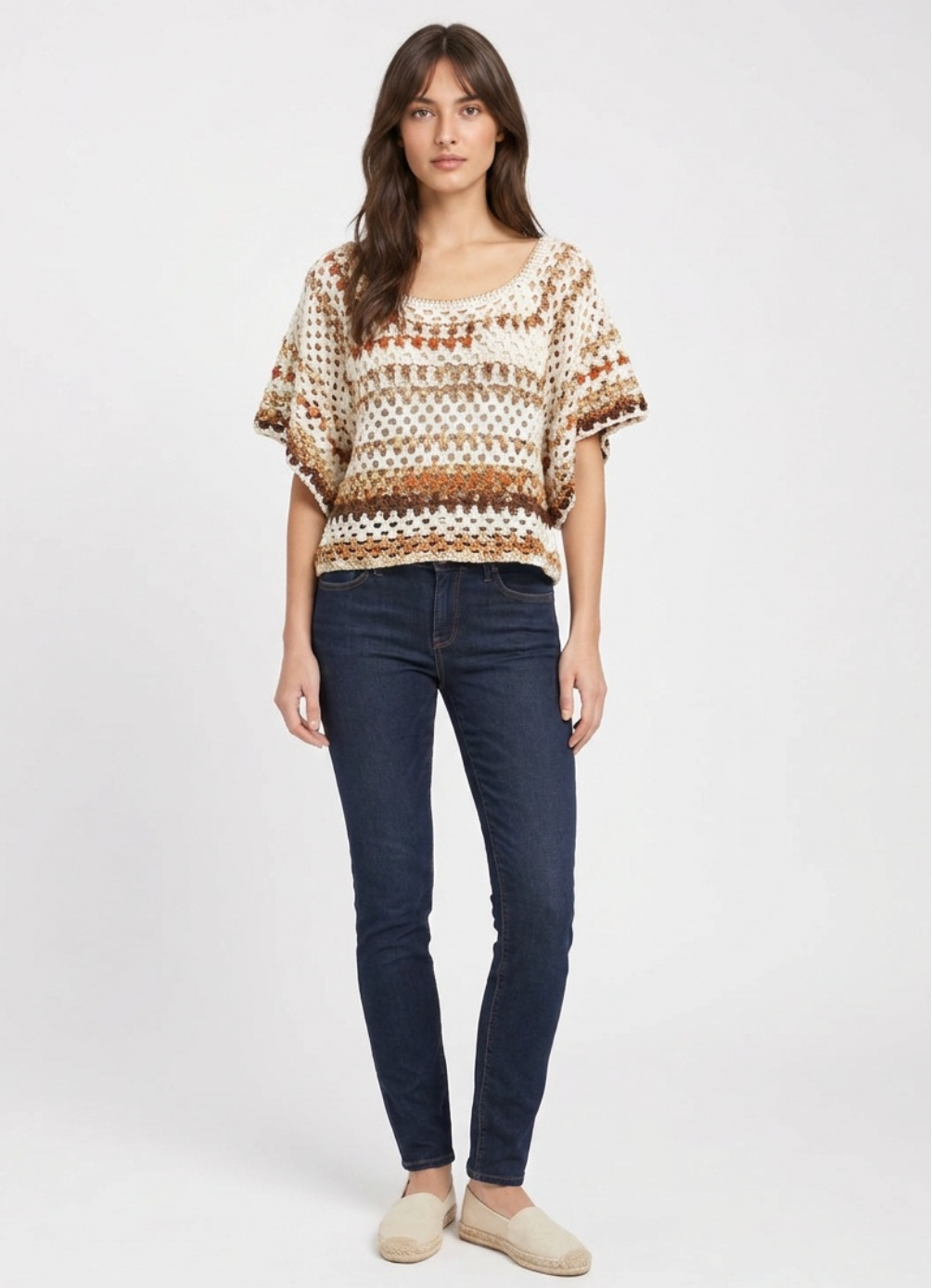 Boxy short-sleeve crochet top in cream with rust and tan open-weave stripes, worn with dark jeans.
