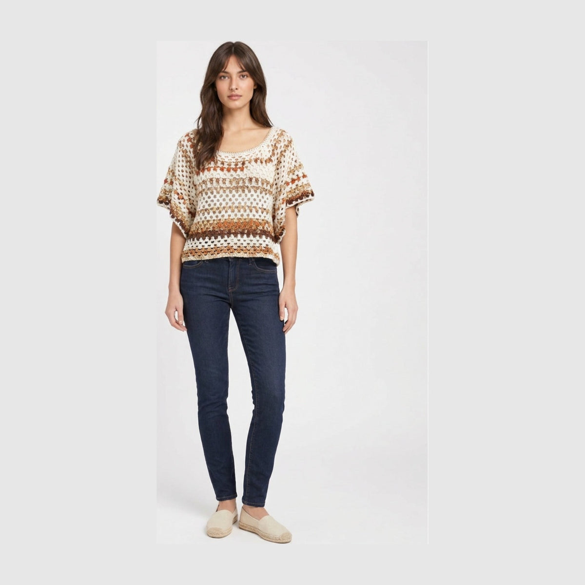 Boxy short-sleeve crochet top in cream with rust and tan open-weave stripes, worn with dark jeans.