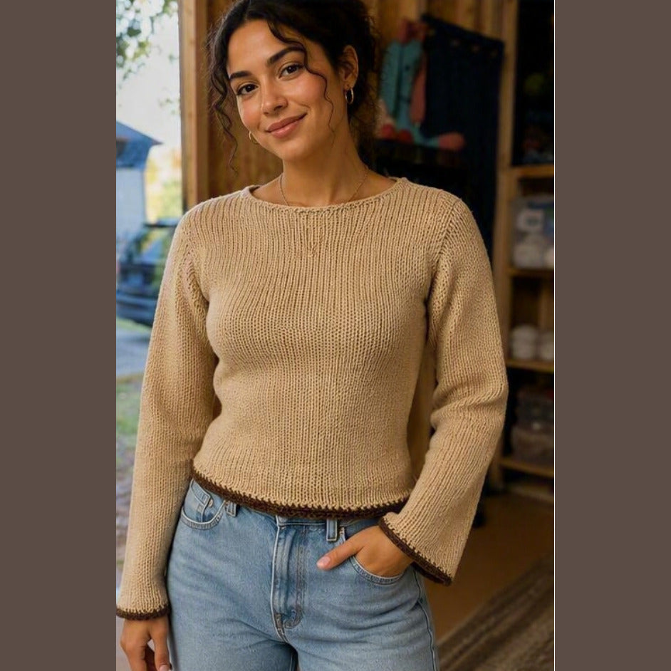 Camel-colored hand-knit boat-neck sweater with dark brown trim at the hem and flared cuffs.