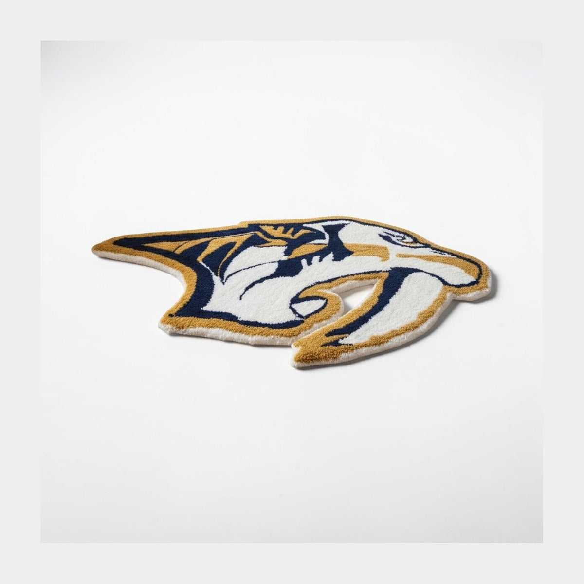 Nashville Predators tufted rug on a white background, cut to the shape of the gold and navy sabertooth logo.