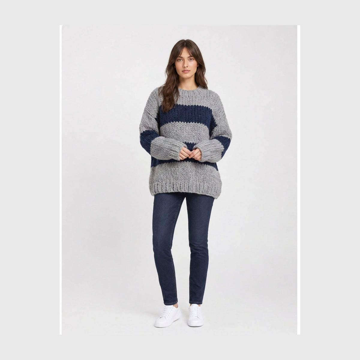 Oversized chunky knit crew-neck sweater in wide grey and navy stripes, worn with dark jeans.